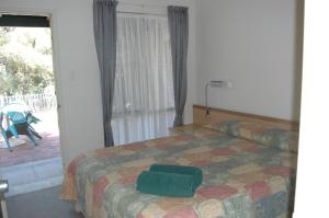 a bedroom with a bed with a green suitcase on it at Collie Forest Motel in Collie