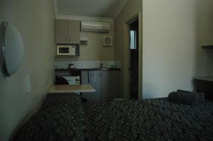 a small room with a bed and a kitchen at Collie Forest Motel in Collie +1 photo