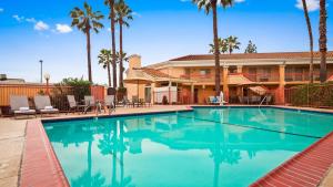 a swimming pool in front of a hotel with palm trees at Best Western Palm Court Inn in Modesto