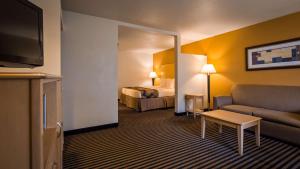 a hotel room with a bed and a couch and a mirror at Best Western Palm Court Inn in Modesto