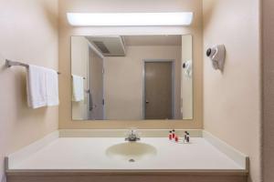 La salle de bains est pourvue d'un lavabo et d'un grand miroir. dans l'établissement Super 8 by Wyndham Hamilton, à Hamilton
