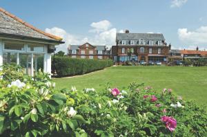 a large yard with flowers in front of a house at Old Hunstanton Le Strange Arms Hotel in Hunstanton
