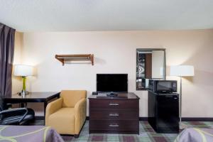 a hotel room with a bed and a desk and a television at Super 8 by Wyndham Campbellsville KY in Campbellsville