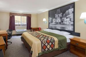 a hotel room with a bed, chair and a painting on the wall at Super 8 by Wyndham Los Angeles Downtown in Los Angeles