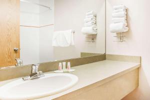 a bathroom with a sink and a mirror and towels at Super 8 by Wyndham Meadow Lake in Meadow Lake