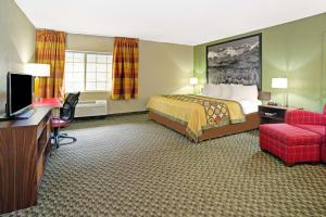 ウィート・リッジにあるSuper 8 by Wyndham Wheat Ridge/Denver Westのベッド、デスク、テレビが備わるホテルルームです。