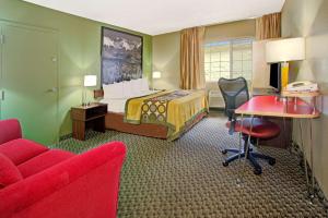 ウィート・リッジにあるSuper 8 by Wyndham Wheat Ridge/Denver Westのベッド、デスク、椅子が備わるホテルルームです。