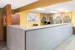 a lobby with a reception counter with yellow walls at Super 8 by Wyndham Bossier City/Shreveport Area in Bossier City