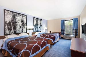 a hotel room with two beds and a flat screen tv at Super 8 by Wyndham Indianola in Indianola