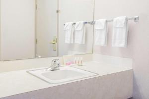 a white bathroom sink sitting under a mirror at Super 8 by Wyndham Lethbridge in Lethbridge