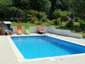 a swimming pool with two lawn chairs next to it at Ferienwohnung am Bodetal mit Wallbox für E-Auto in Thale