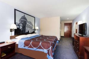 a hotel room with a bed and a flat screen tv at Super 8 by Wyndham Indianola in Indianola