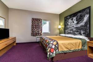 a hotel room with a bed and a flat screen tv at Super 8 by Wyndham Beresford in Beresford