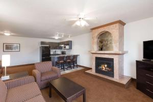 a living room with a fireplace and a kitchen at Super 8 by Wyndham Vermilion AB in Vermilion