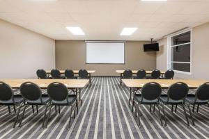 einen Konferenzraum mit Tischen, Stühlen und einem Whiteboard in der Unterkunft Super 8 by Wyndham Mont Laurier in Mont-Laurier