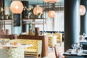 a restaurant with yellow chairs and tables and pendant lights at Radisson Collection Royal Hotel, Copenhagen in Copenhagen