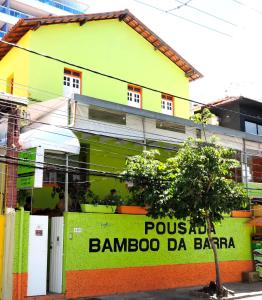 a yellow and green building with a tree in front of it at Pousada Bamboo da Barra in Salvador