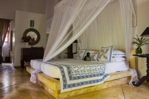 a bedroom with a canopy bed with white sheets and pillows at Why House in Unawatuna