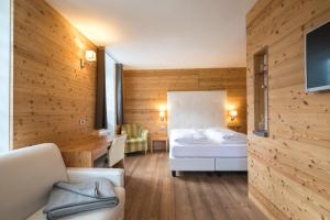 a bedroom with a bed and a desk in a room at Hotel Costabella in Passo San Pellegrino