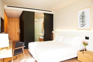 a bedroom with a white bed and a desk with a chair at Hotel Arima & Spa - Small Luxury Hotels in Donostia-San Sebastián