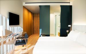 a bedroom with a bed and a desk with a television at Hotel Arima & Spa - Small Luxury Hotels in Donostia-San Sebastián