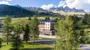 a large building on a hill with mountains in the background at Hotel Costabella in Passo San Pellegrino