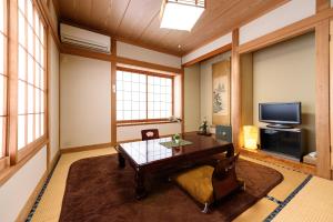 a living room with a table and a tv at Yufuin Onsen Oyado Jinnouchi in Yufuin