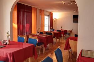 ein Restaurant mit Tischen und Stühlen mit rotem Tischtuch in der Unterkunft Garni Hotel Rödelheimer Hof in Frankfurt am Main