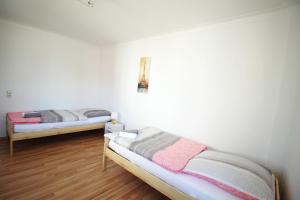 two beds in a room with white walls and wooden floors at Apartment Merklingen in Merklingen