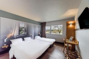 um quarto com uma grande cama branca e uma televisão em B&B HOTEL Besançon Chateaufarine em Besançon