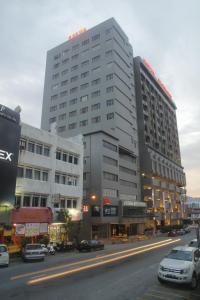 een groot gebouw in een stadsstraat met geparkeerde auto's bij Hotel Excelsior Ipoh in Ipoh