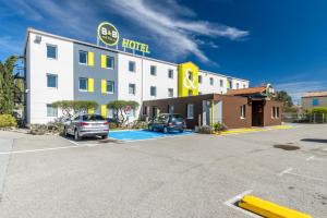 een hotel met twee auto's geparkeerd op een parkeerplaats bij B&B HOTEL Brignoles in Brignoles