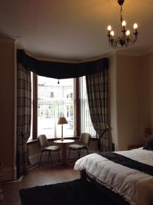 a bedroom with a bed and a window with a table and chairs at Hannahs Guesthouse in Aberdeen