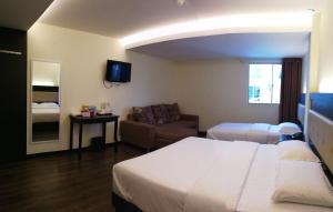 a hotel room with a bed and a couch at Hotel Zuhra in Sibu