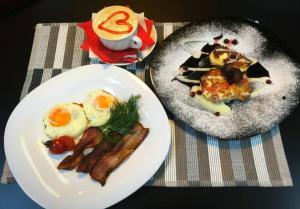 コヴロフにあるMini Hotel Agoraの卵とベーコンを盛り付けたテーブルの上に2皿