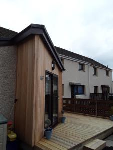 a wooden building on a deck in front of a house at Byers Guest house in Banavie