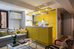 uma sala de estar com um sofá e uma cozinha com armários amarelos em San Carlo Apartment em Lucca