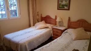 a bedroom with two beds and a lamp on a night stand at Casa Rural La Cucurrumacha in Navalosa