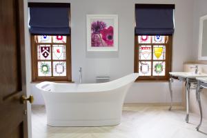 a white bath tub in a room with stained glass windows at Lainston House in Winchester
