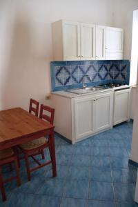 una cucina con armadi bianchi, tavolo e lavandino di Maridea - Spiaggia Sant' Antonio a Ponza