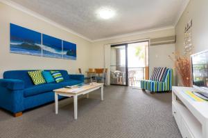 a living room with a blue couch and a table at Beaches On Wave Street in Gold Coast