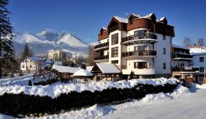 a large building with snow on the ground at APLEND Vila Beatrice in Vysoke Tatry - Tatranska Lomnica.