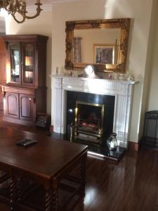 a living room with a fireplace with a table and a mirror at Lios Daire in Killarney