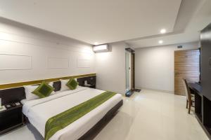 a bedroom with a large bed and a desk at Treebo Trend Raj Premier - Indiranagar in Bangalore