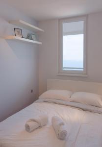 a white bed in a room with a window at Razgled/The View in Koper