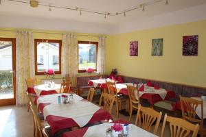 ein Restaurant mit roten und weißen Tischen und Stühlen in der Unterkunft Hotel garni Vogelsang in Bad Füssing