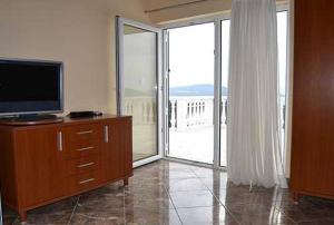 a living room with a television and a sliding glass door at Apartments Barisic Hrvatskih Žrtava 404 Seget Vranjica in Trogir