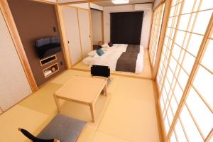 a bedroom with a bed and a table and a tv at Tabinoteitaku Okinawa Nakijin HOMANN CONCEPT in Nakijin