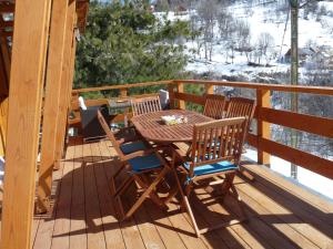 a wooden table and chairs on a deck with snow at Les marmottes d Estenc in Estenc