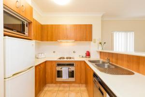 a small kitchen with wooden cabinets and a sink at Beaches On Wave Street in Gold Coast